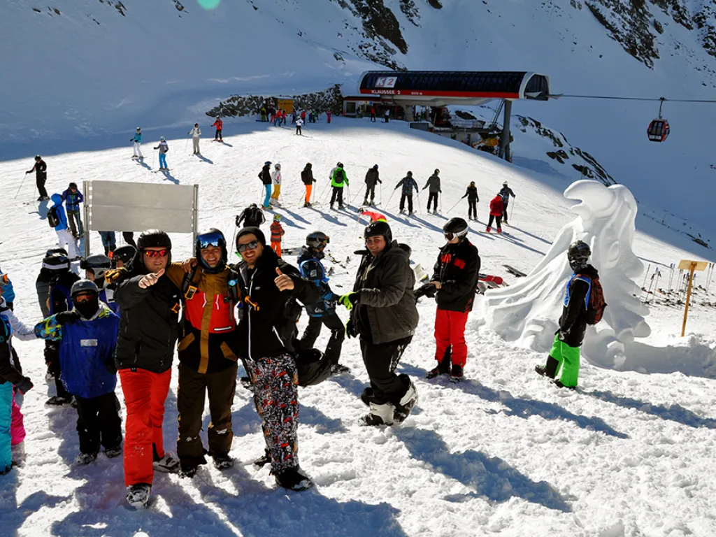 Gruppe steht neben Schneeskulpturen an der Bergstation.